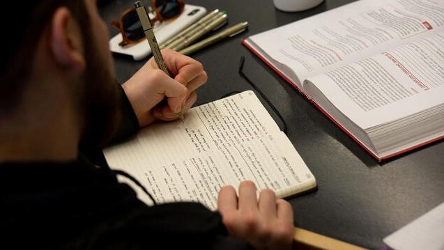 Student writes notes in a notebook in class.